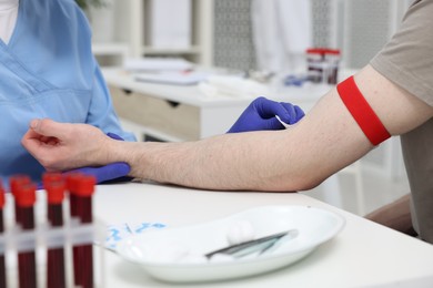 Laboratory testing. Doctor taking blood sample from patient at white table in hospital, closeup