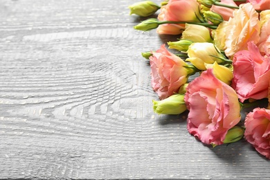 Photo of Beautiful fresh Eustoma flowers on wooden table, space for text