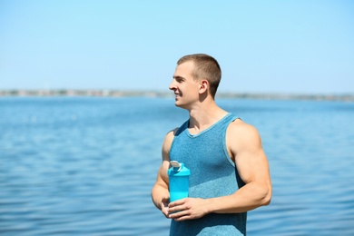 Photo of Athletic young man with protein shake at riverside