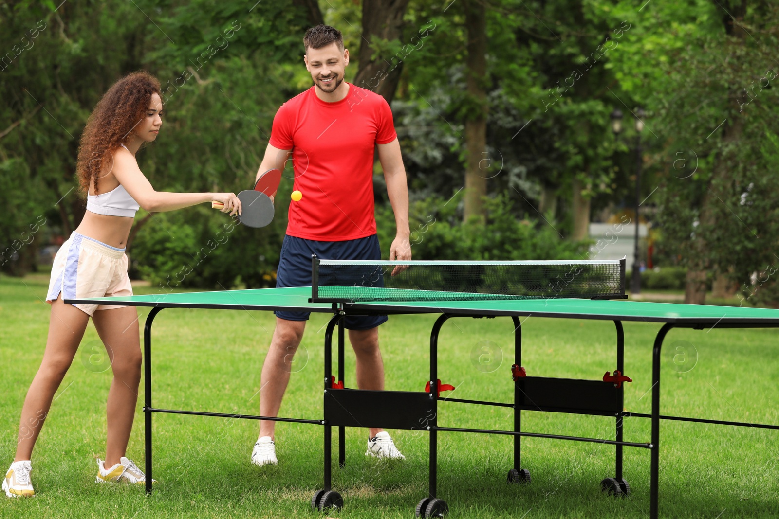 Photo of Friends playing ping pong outdoors on summer day