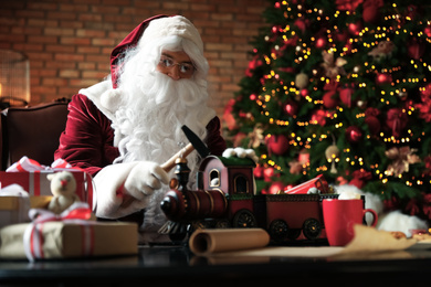 Santa Claus making new toy for Christmas in workshop