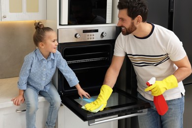 Photo of Spring cleaning. Father and daughter tidying up oven in kitchen together