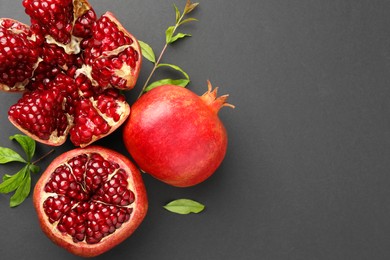 Fresh ripe pomegranates and leaves on grey background, top view. Space for text