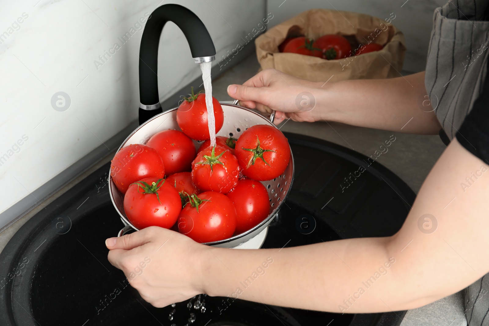 Photo of Woman washing ripe tomatoes in sink, closeup