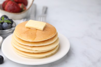 Delicious pancakes with butter and honey on white marble table, closeup. Space for text