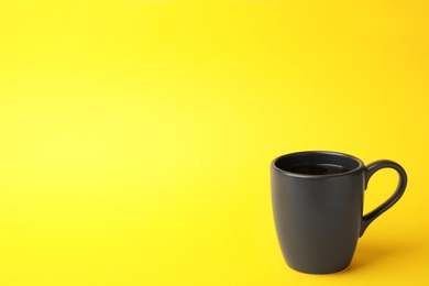 Photo of Black ceramic cup with hot aromatic coffee on color background