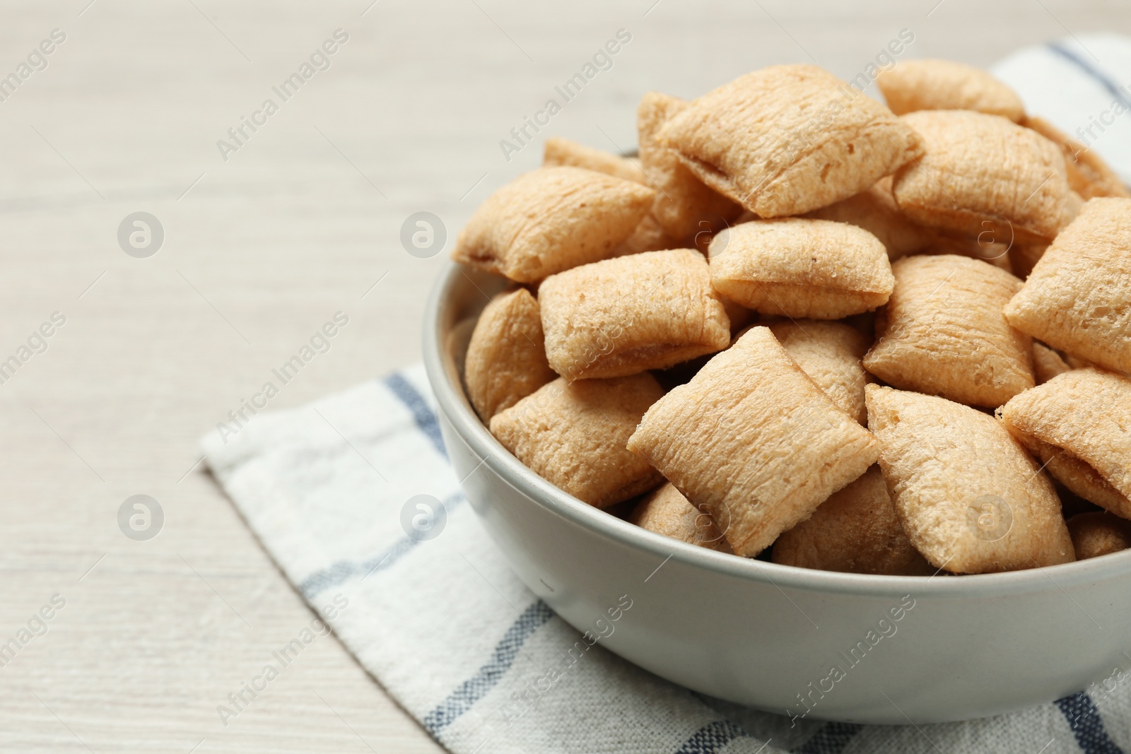 Photo of Bowl of sweet crispy corn pads on white wooden table, closeup view with space for text. Breakfast cereal