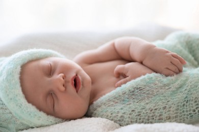 Cute newborn baby in warm hat sleeping on white plaid, closeup