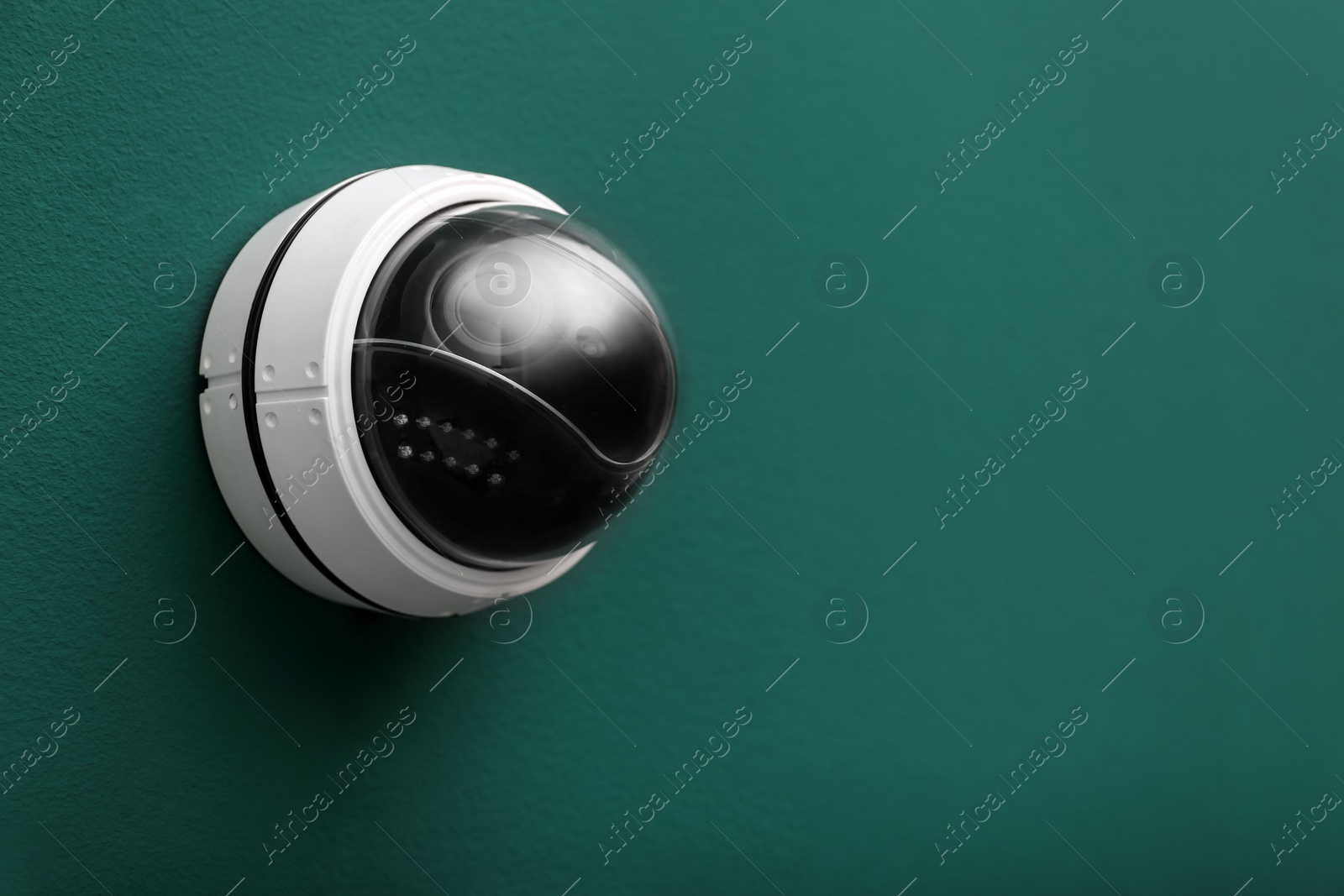 Photo of Modern CCTV security camera on green wall. Space for text