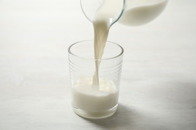 Pouring milk into glass on white table