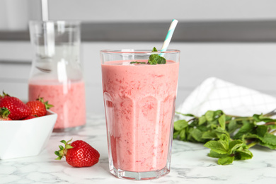 Photo of Tasty strawberry smoothie with mint in glass on white marble table