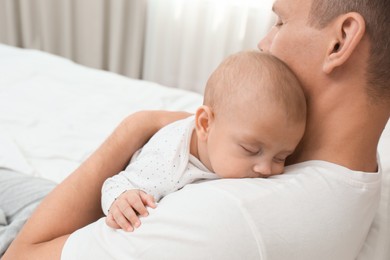 Photo of Father holding his cute sleeping baby on bed at home