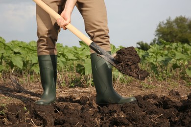 Worker digging soil with shovel outdoors, closeup