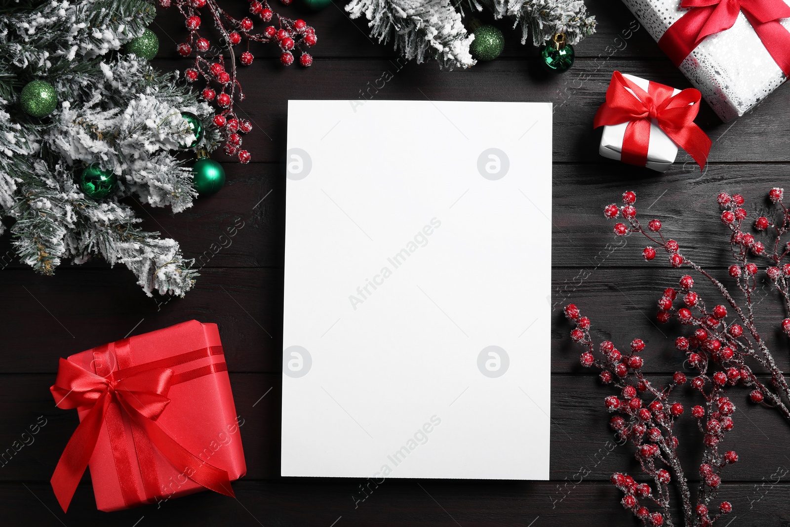 Photo of Flat lay composition with blank paper, gift boxes and Christmas decor on wooden table, space for text. Letter to Santa