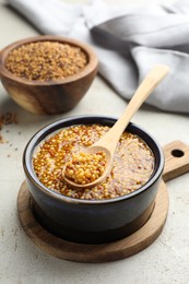 Photo of Whole grain mustard in bowl and spoon on light table