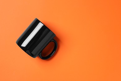 Photo of One black ceramic mug on orange background, top view. Space for text