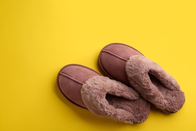 Pair of stylish soft slippers on yellow background, flat lay. Space for text