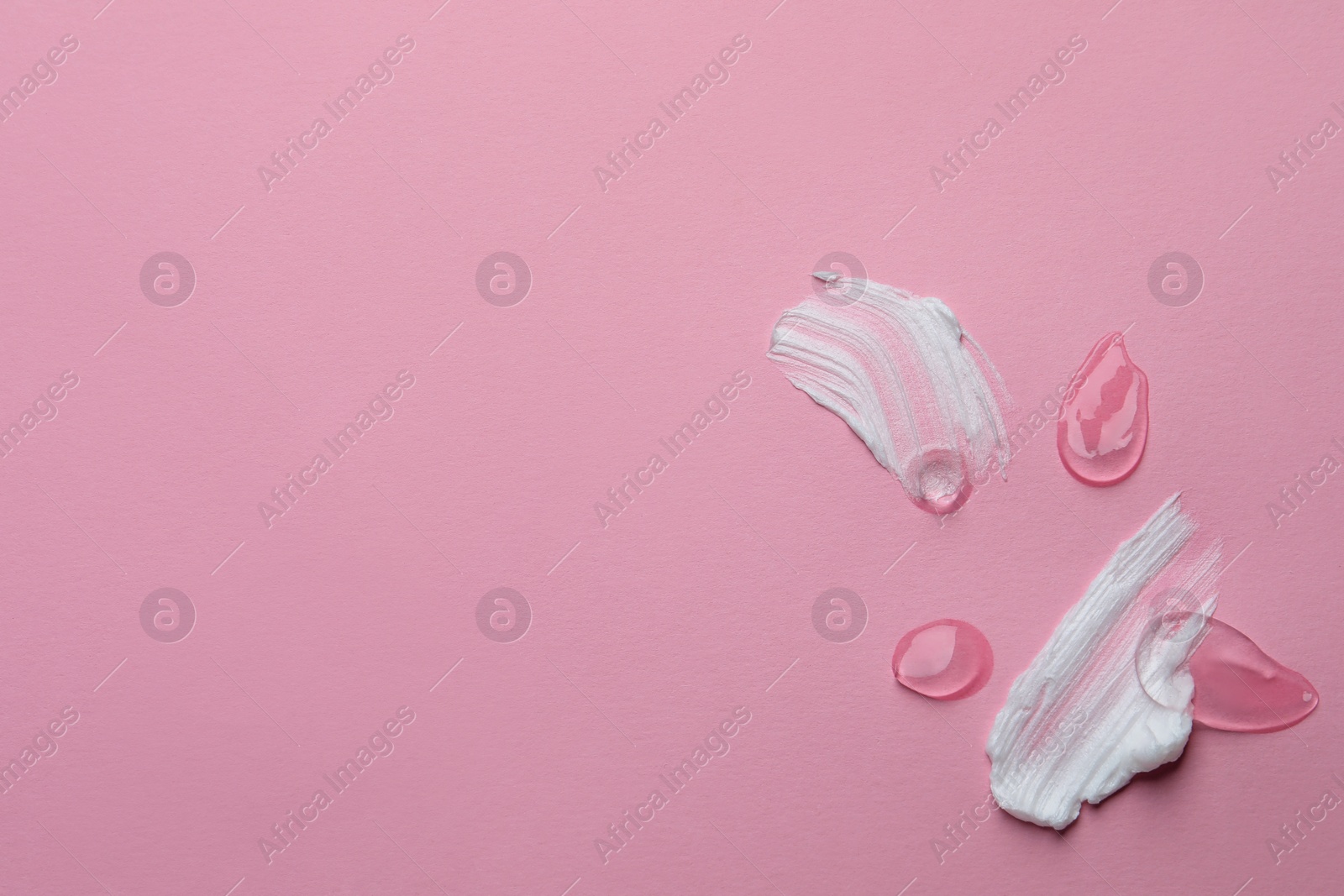 Photo of Samples of cosmetic gel and cream on pink background, top view. Space for text