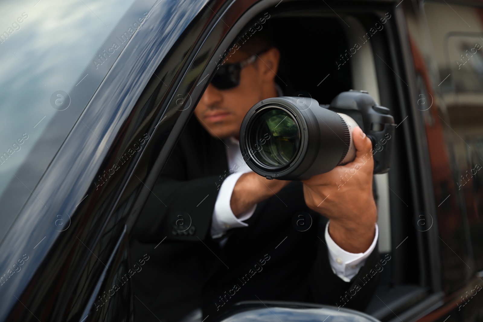 Photo of Private detective with camera spying from car, focus on lens