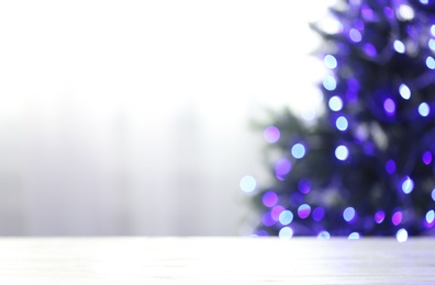 Photo of Empty table and blurred fir tree with violet Christmas lights on background, bokeh effect. Space for design