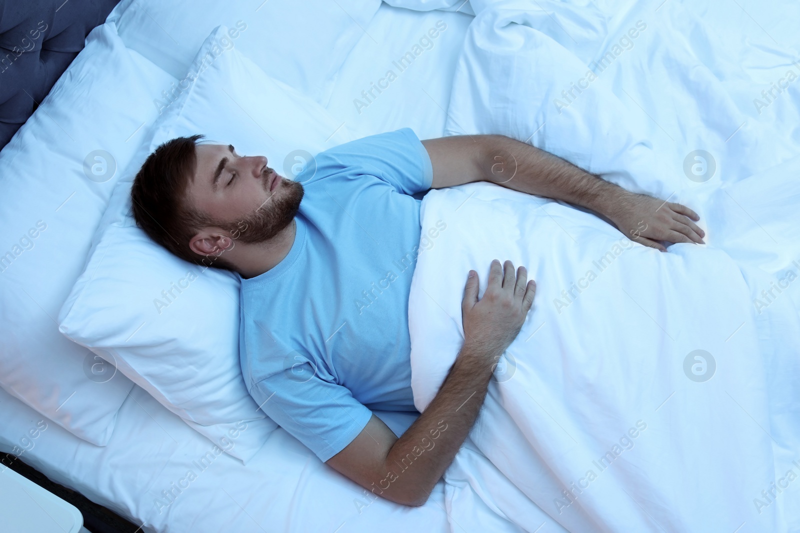 Photo of Young handsome man sleeping in bed at night