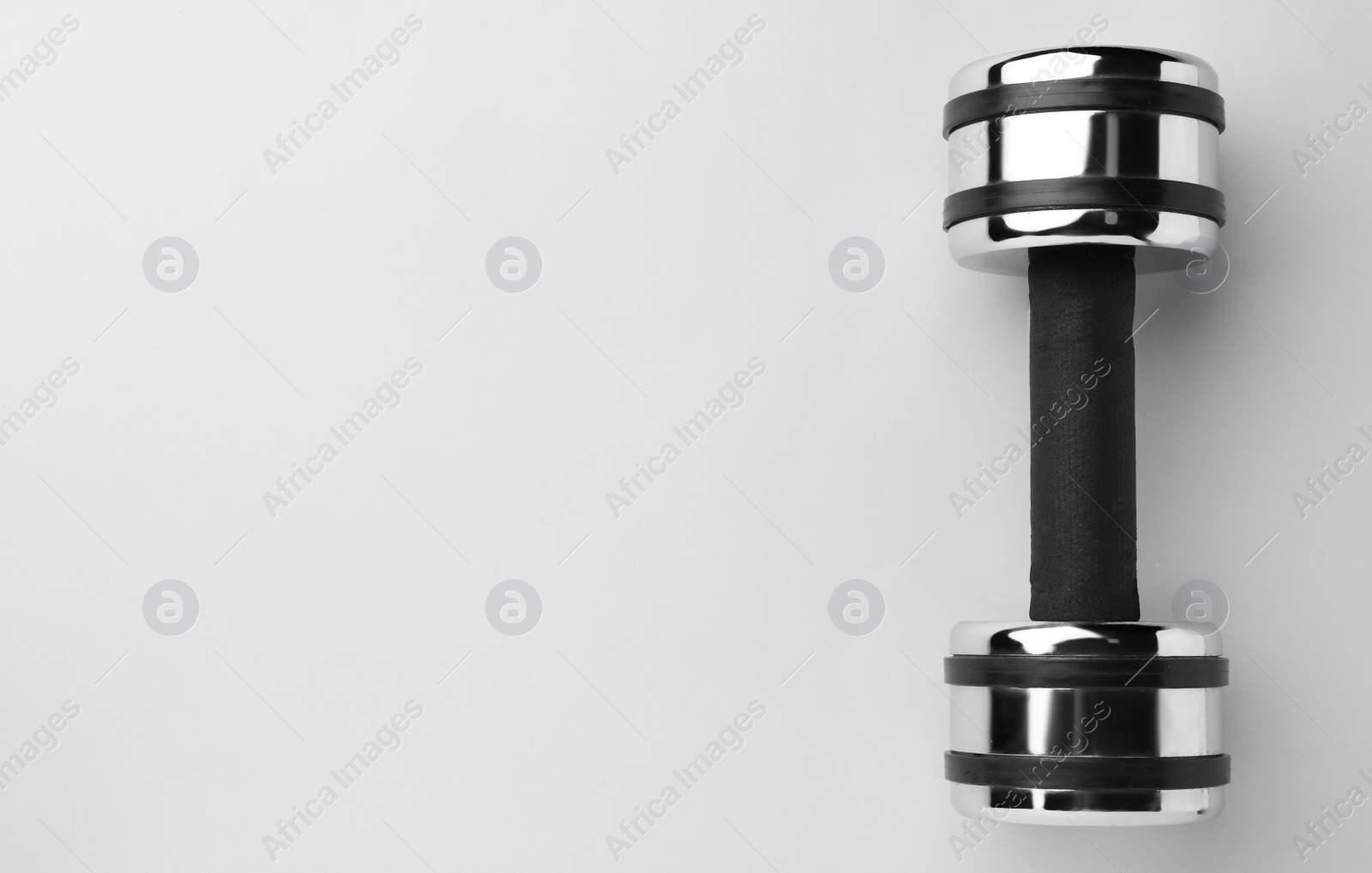 Photo of Metal dumbbell on light background, top view. Space for text