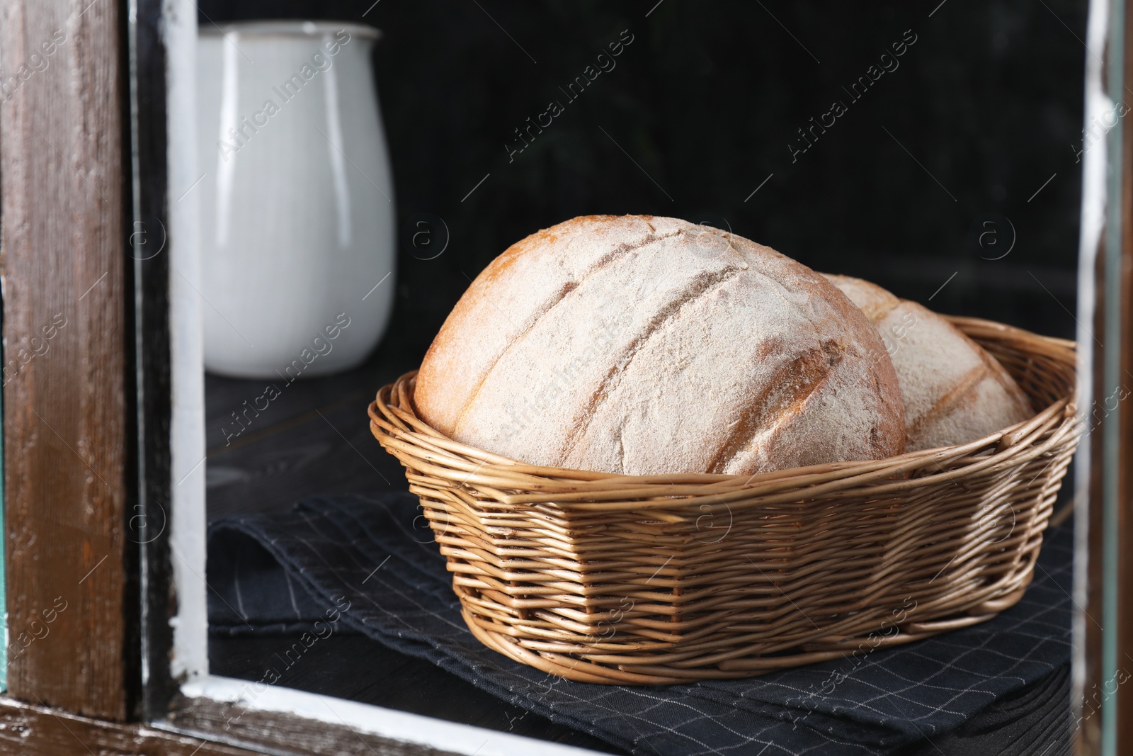 Photo of Fresh homemade bread in wicker basket, view through window