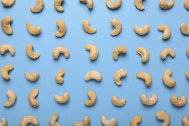 Photo of Many tasty cashew nuts on light blue background, top view