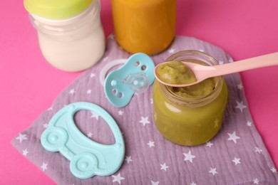 Healthy baby food, pacifier and toy on pink background