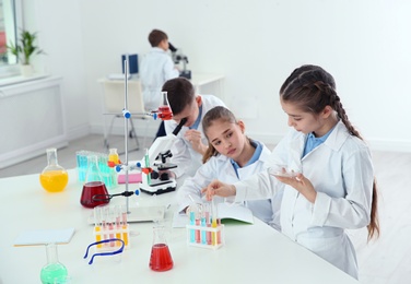 Photo of Smart pupils making experiment at table in chemistry class