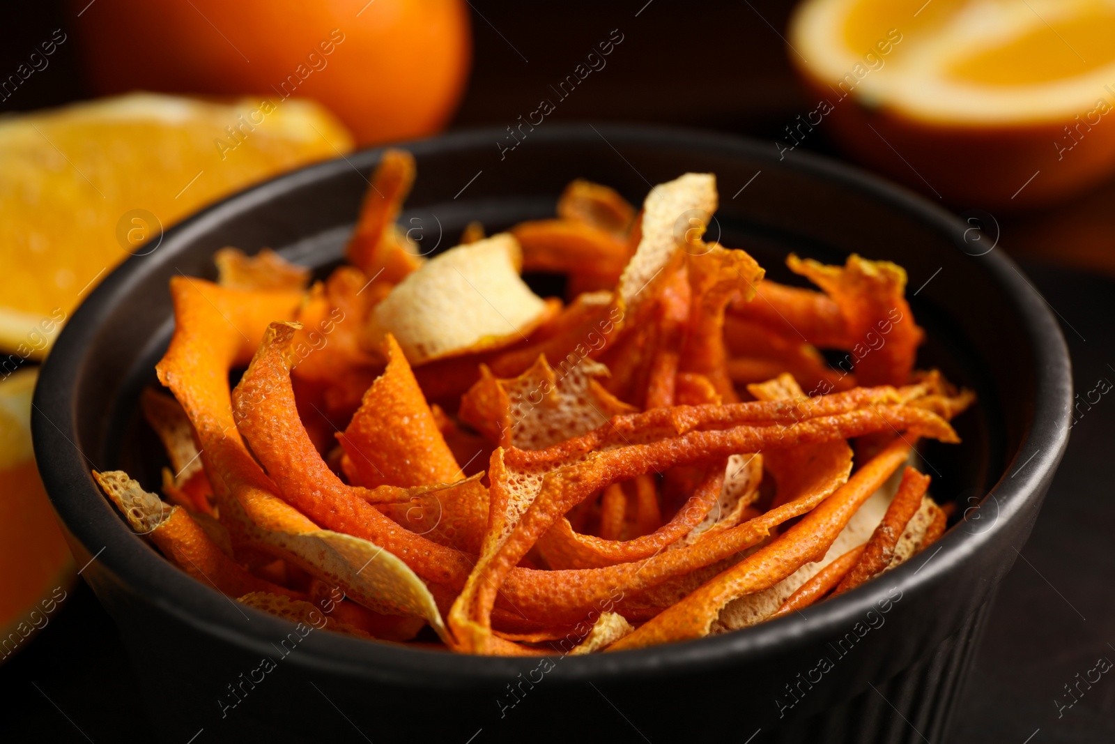 Photo of Bowl with dry orange peels and fresh fruits on table, closeup