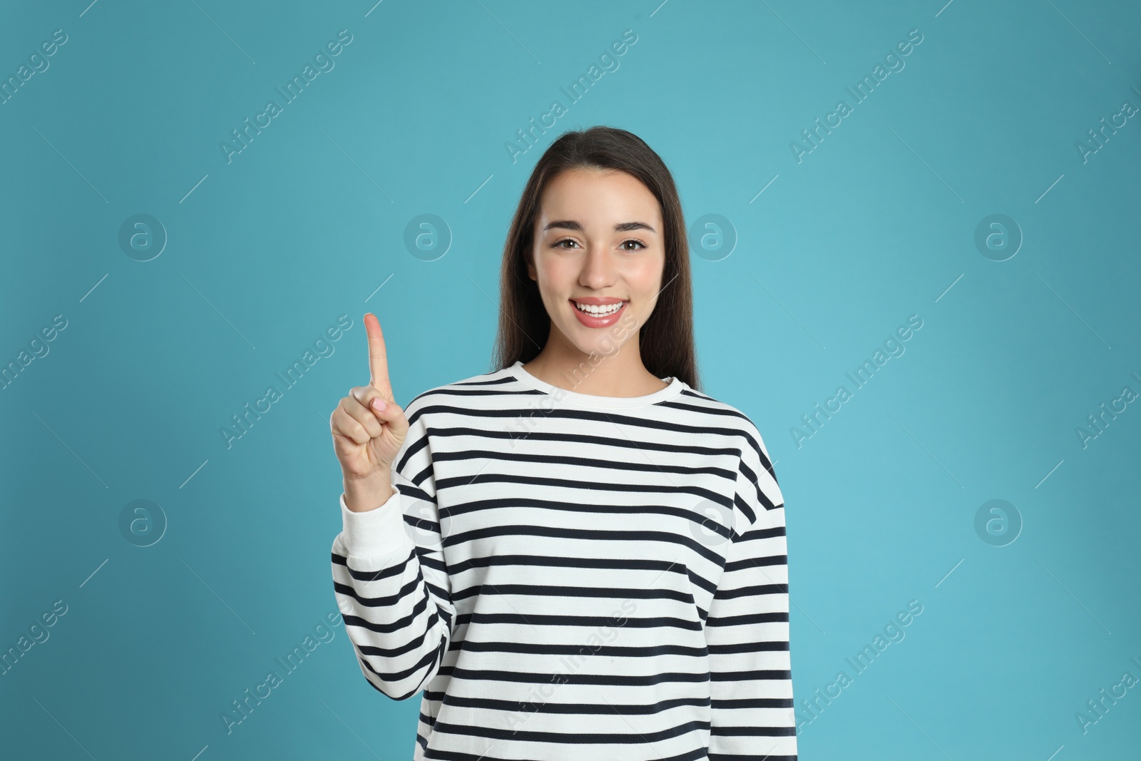 Photo of Woman showing number one with her hand on light blue background