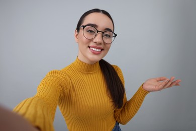 Photo of Smiling young woman taking selfie on grey background