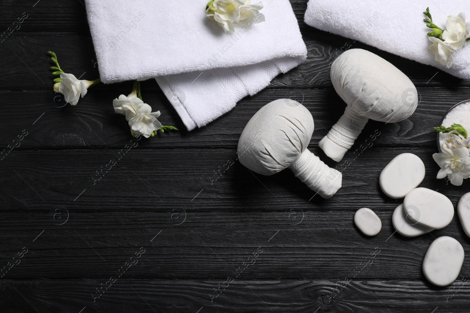 Photo of Flat lay composition with herbal massage bags and other spa products on black wooden table, space for text