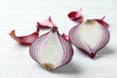 Photo of Halves of red onion on white wooden table