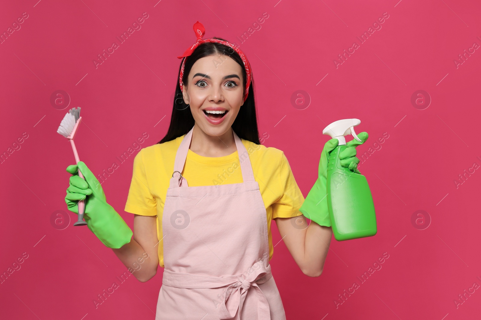 Photo of Emotional housewife with detergent and brush on pink background