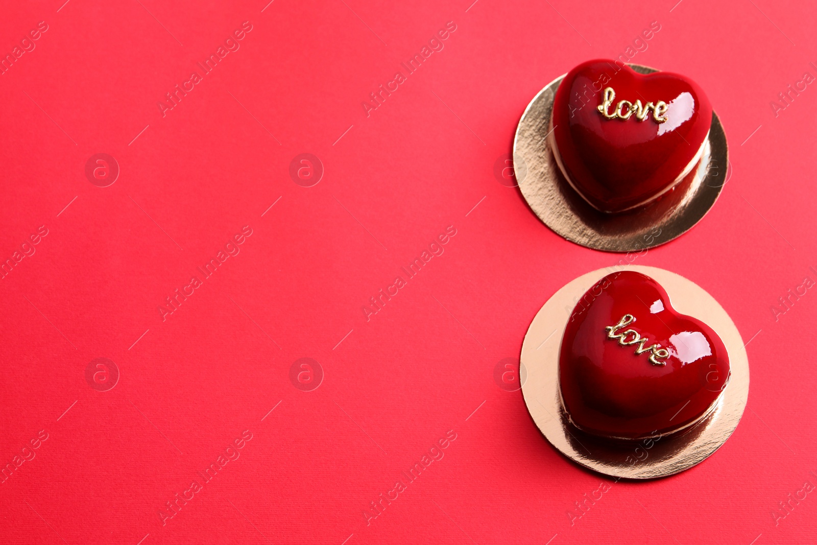 Photo of St. Valentine's Day. Delicious heart shaped cakes on red background, above view. Space for text