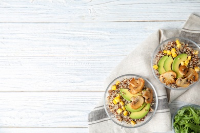 Healthy quinoa salad with vegetables in bowls on table, top view. Space for text