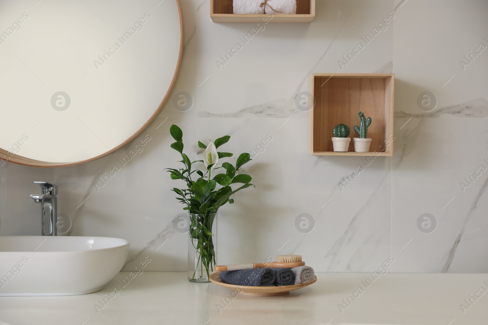 Photo of Beautiful green plants near vessel sink on countertop in bathroom. Interior design