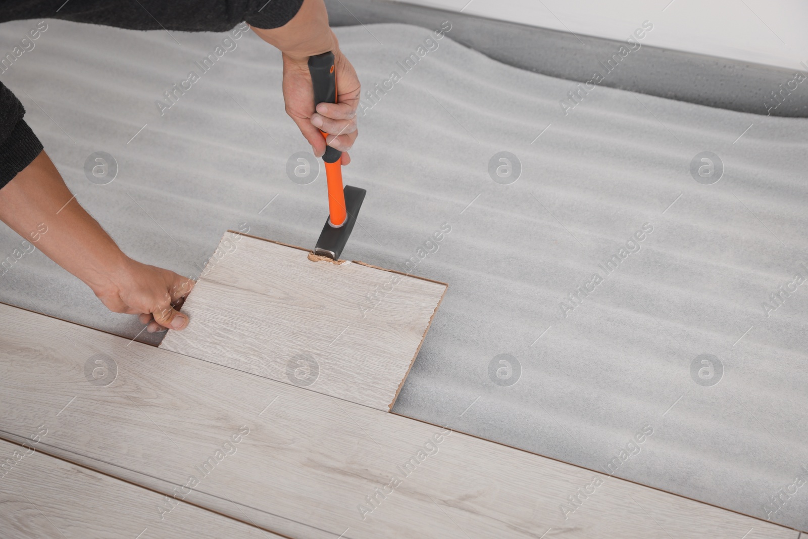 Photo of Worker installing new laminate flooring in room, closeup