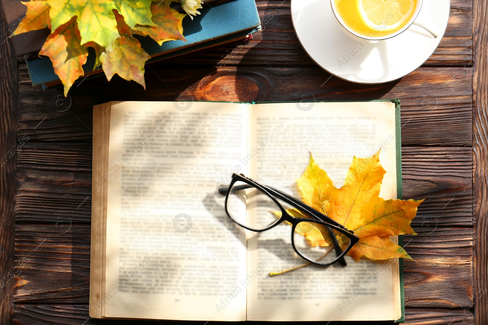 Photo of Maple leaves, book and glasses on wooden table, flat lay. Autumn atmosphere