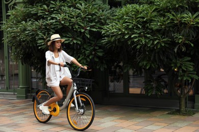 Photo of Beautiful young woman riding bicycle outdoors. Space for text