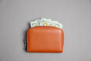 Photo of Stylish brown leather purse with dollar banknotes on light grey background, top view