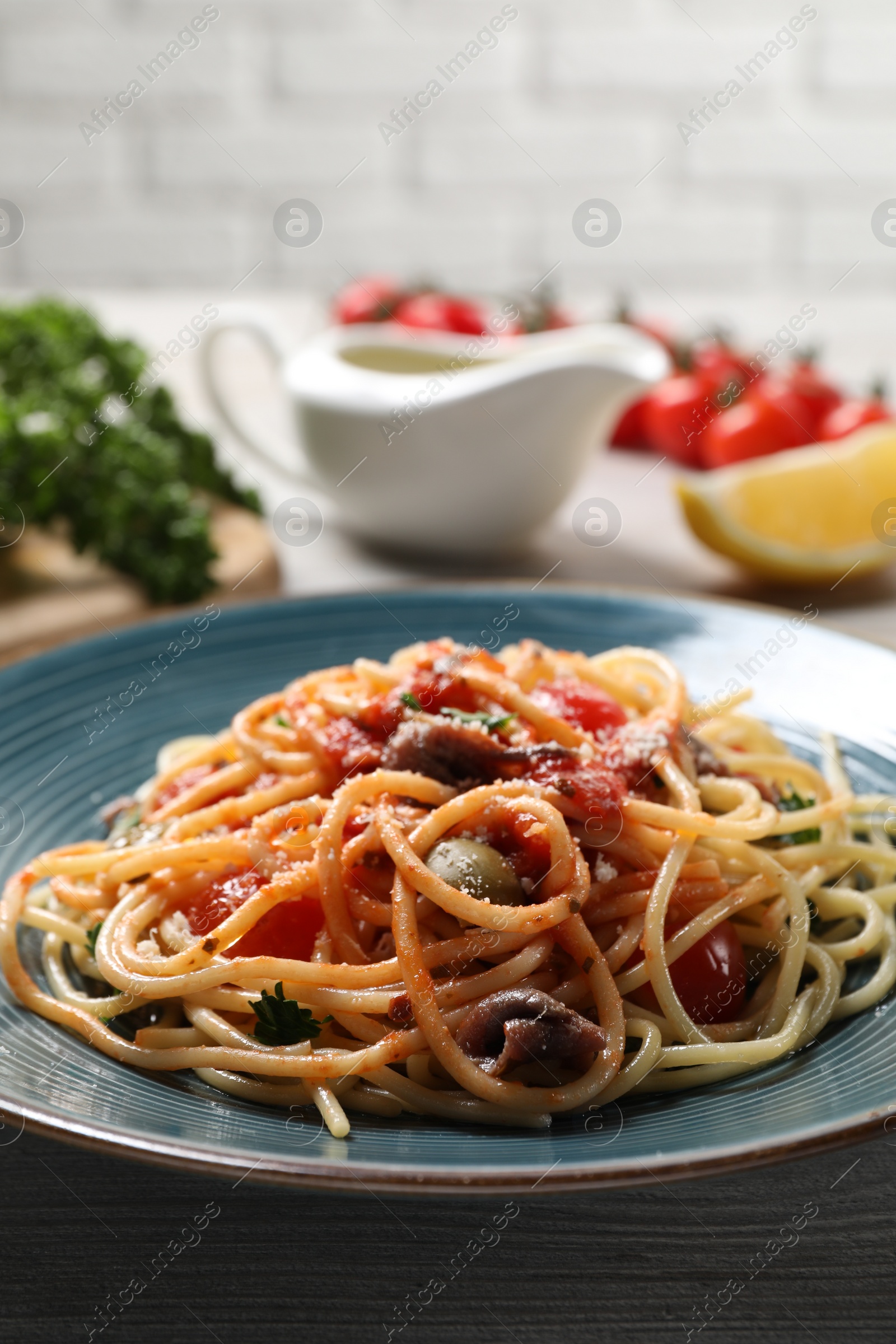 Photo of Delicious pasta with anchovies, tomatoes and parmesan cheese on table, closeup