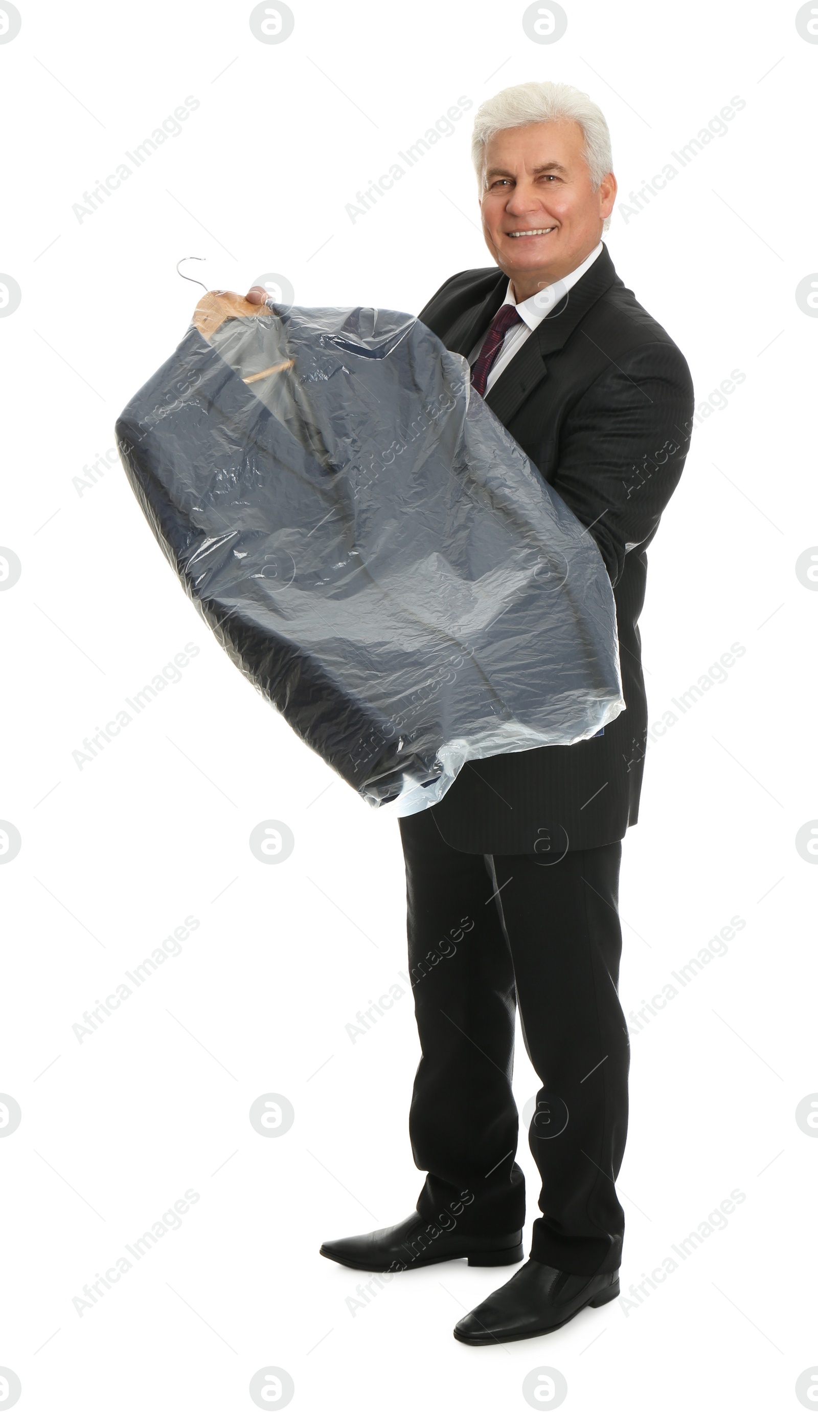 Photo of Senior man holding hanger with jacket in plastic bag on white background. Dry-cleaning service