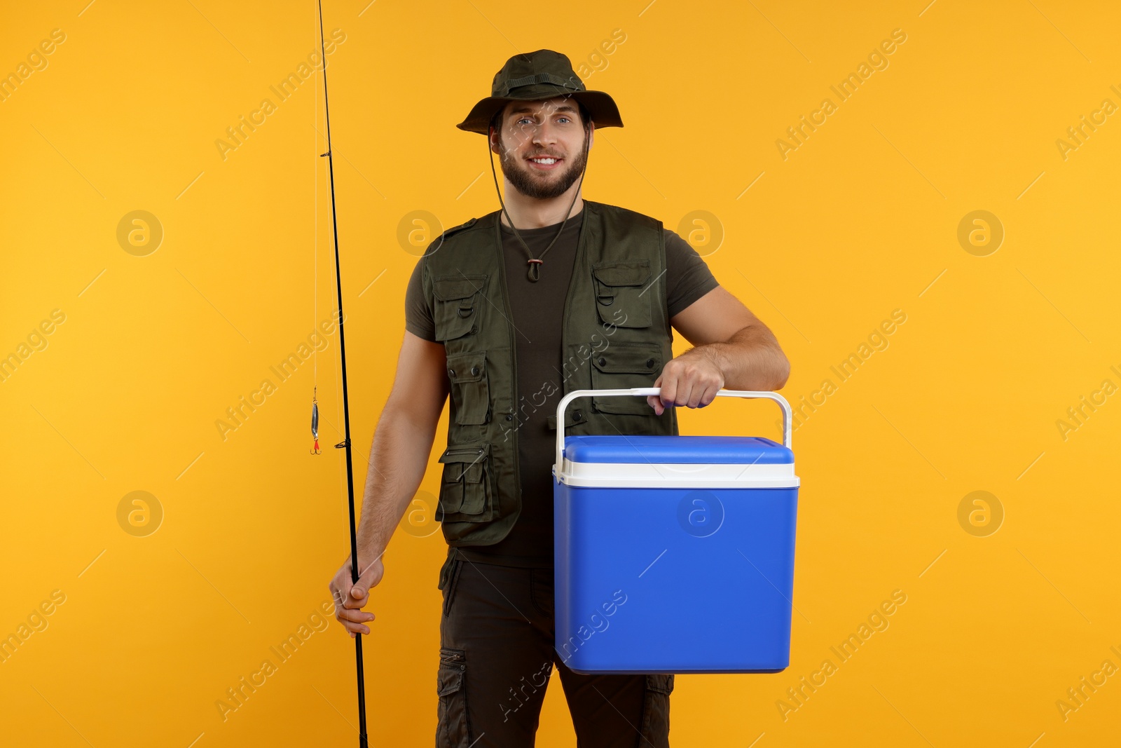 Photo of Fisherman with fishing rod and cool box on yellow background