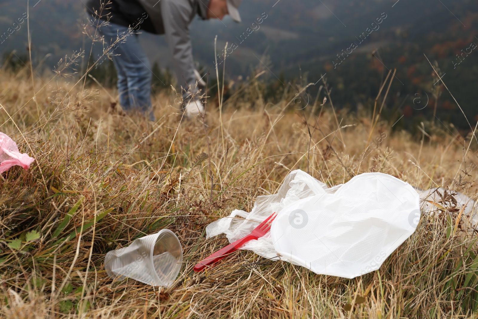 Photo of Man collecting garbage in nature, focus on plastic trash