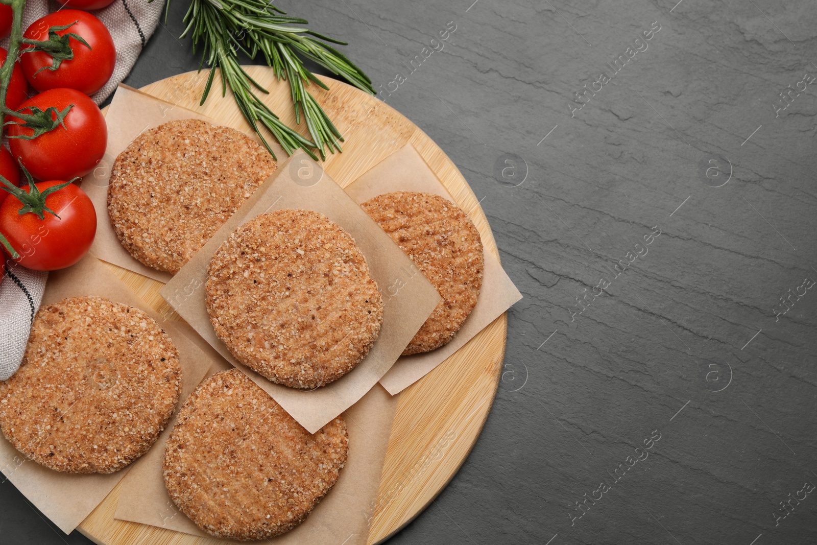 Photo of Raw vegan cutlets with breadcrumbs on black table, flat lay. Space for text