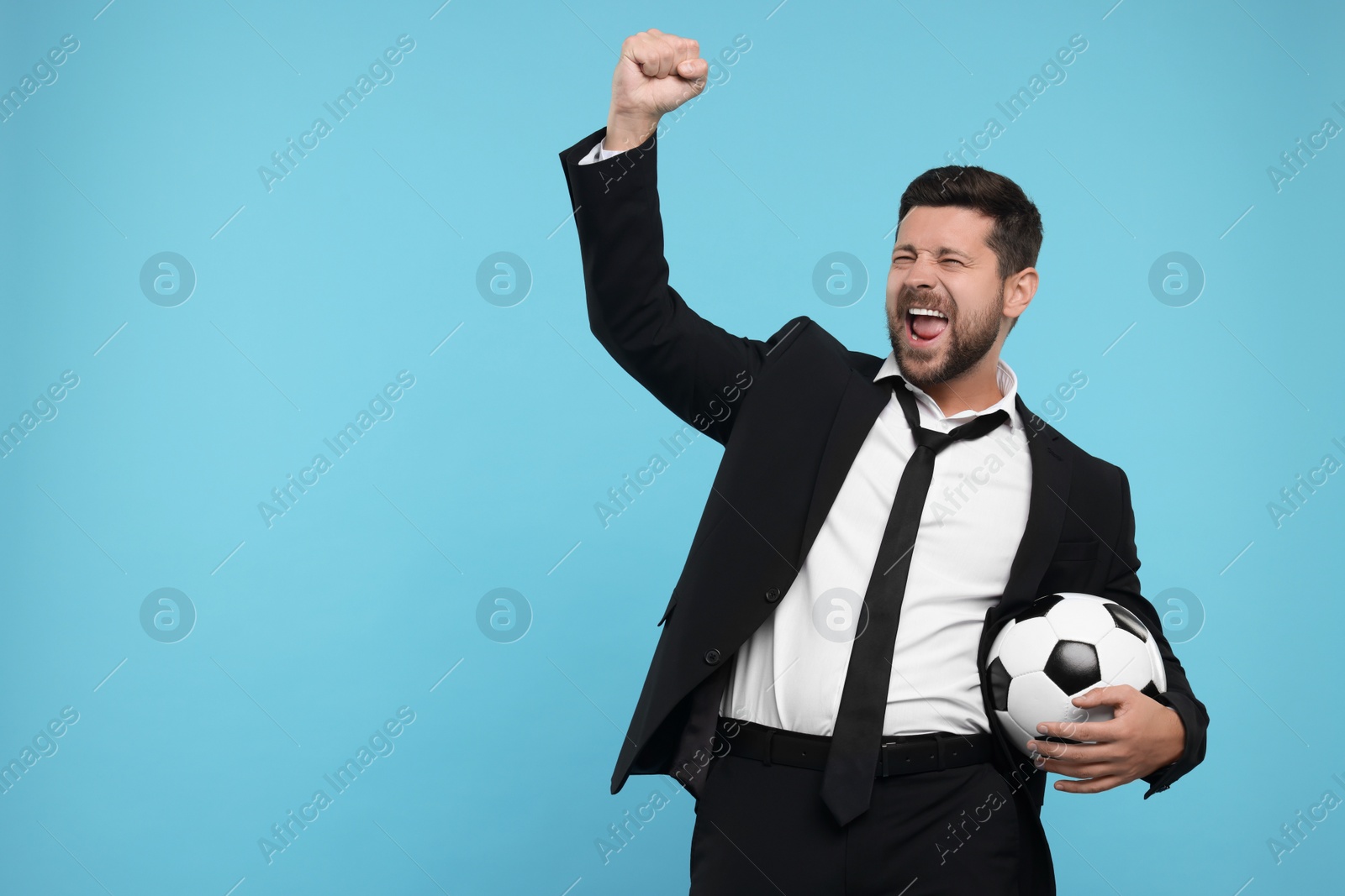 Photo of Emotional sports fan with ball celebrating on light blue background. Space for text