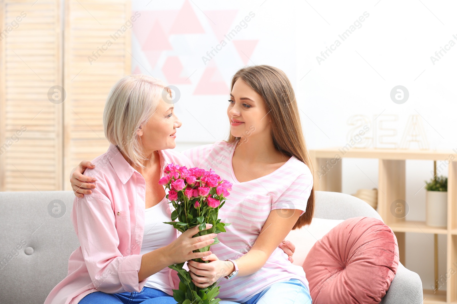 Photo of Young daughter congratulating her mature mother at home. Happy Women's Day
